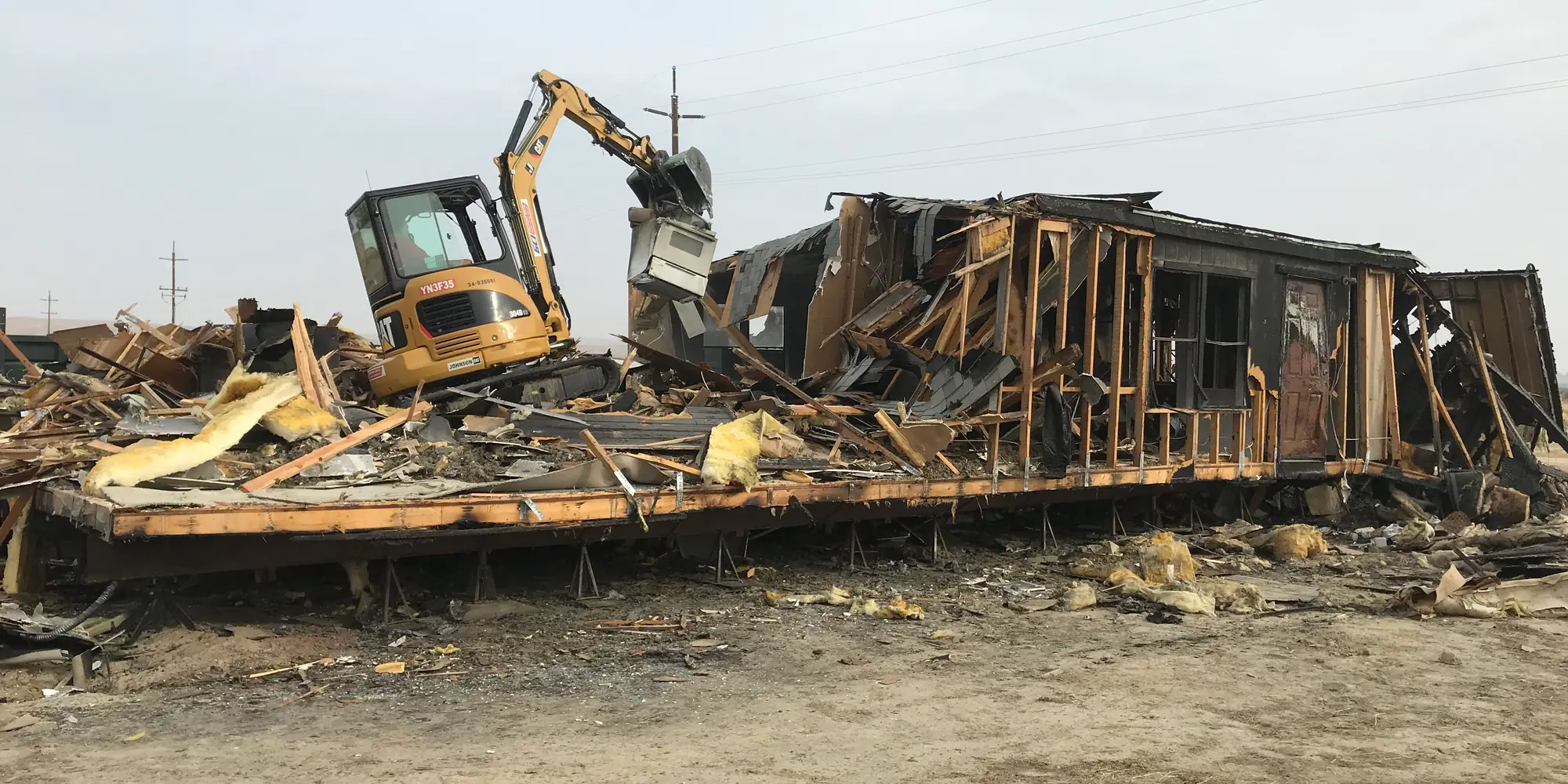 Excavator working a demolition debris pile on an ACH Services job